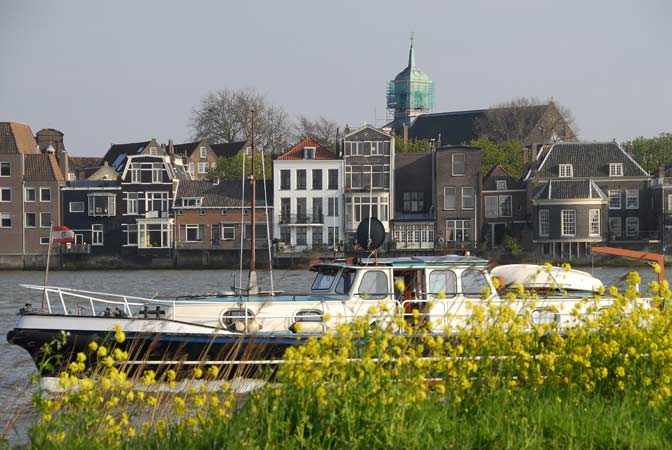 Het herenhuis, de kade en de rivierzijde met terassen boven de Oude Maas - met belendende panden aan de rivier.