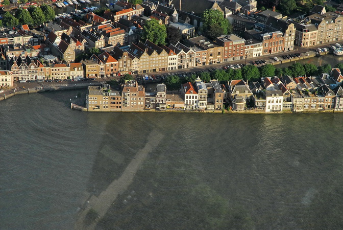Een luchtfoto van de Dordtse rivieroever met haar riante kadewoningen met balkons en terassen aan en boven de Oude Maas - met belendende panden aan de rivier.